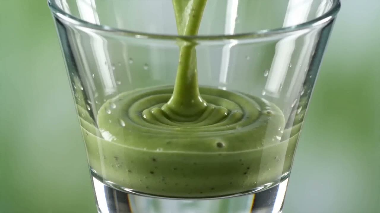 AI-genereret wellnessannonce med en grøn smoothie, der hældes op, og ingredienser i slowmotion.
