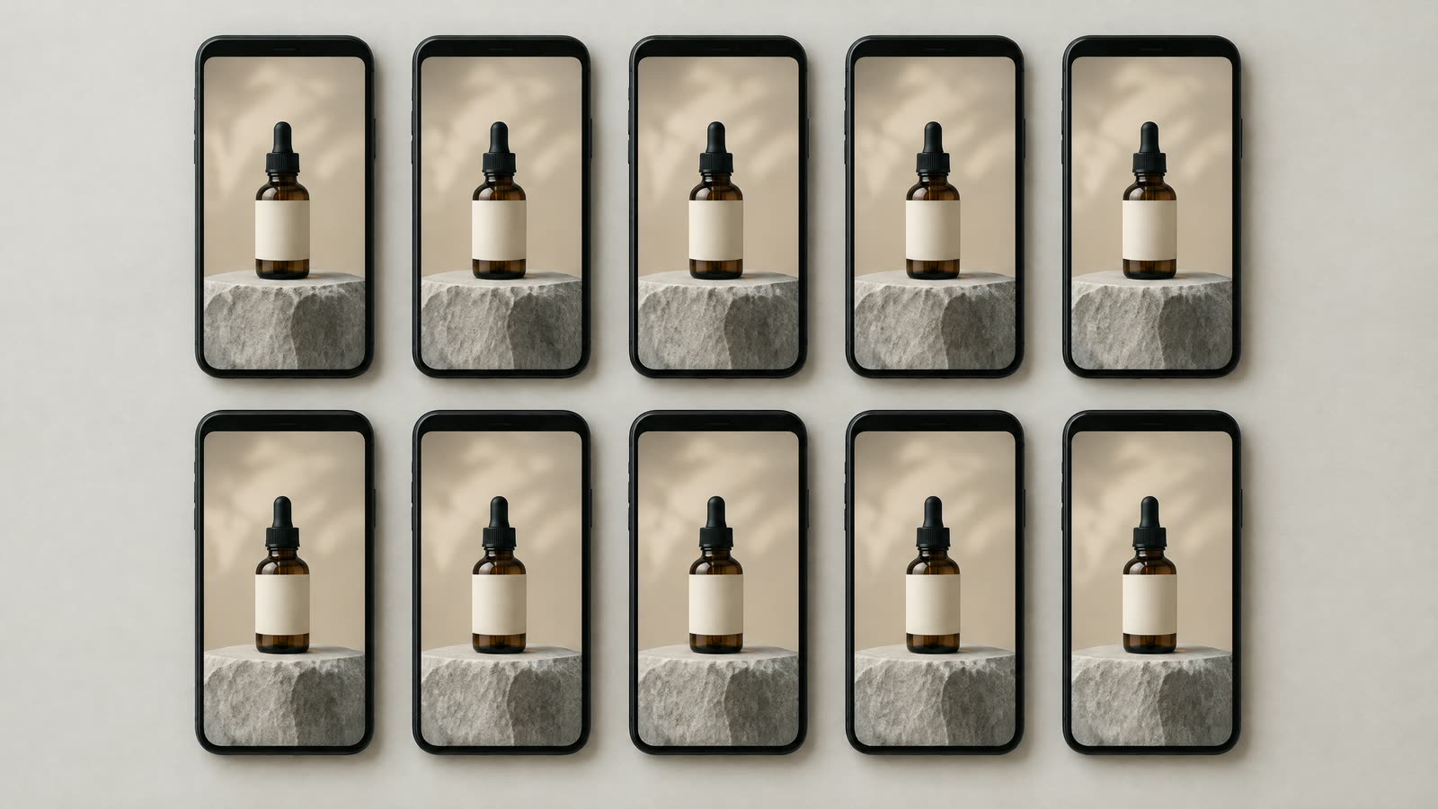 Ten identical smartphones laid out in two rows on a pale table, each screen showing the same vertical ad of an unlabeled amber serum bottle on a stone plinth