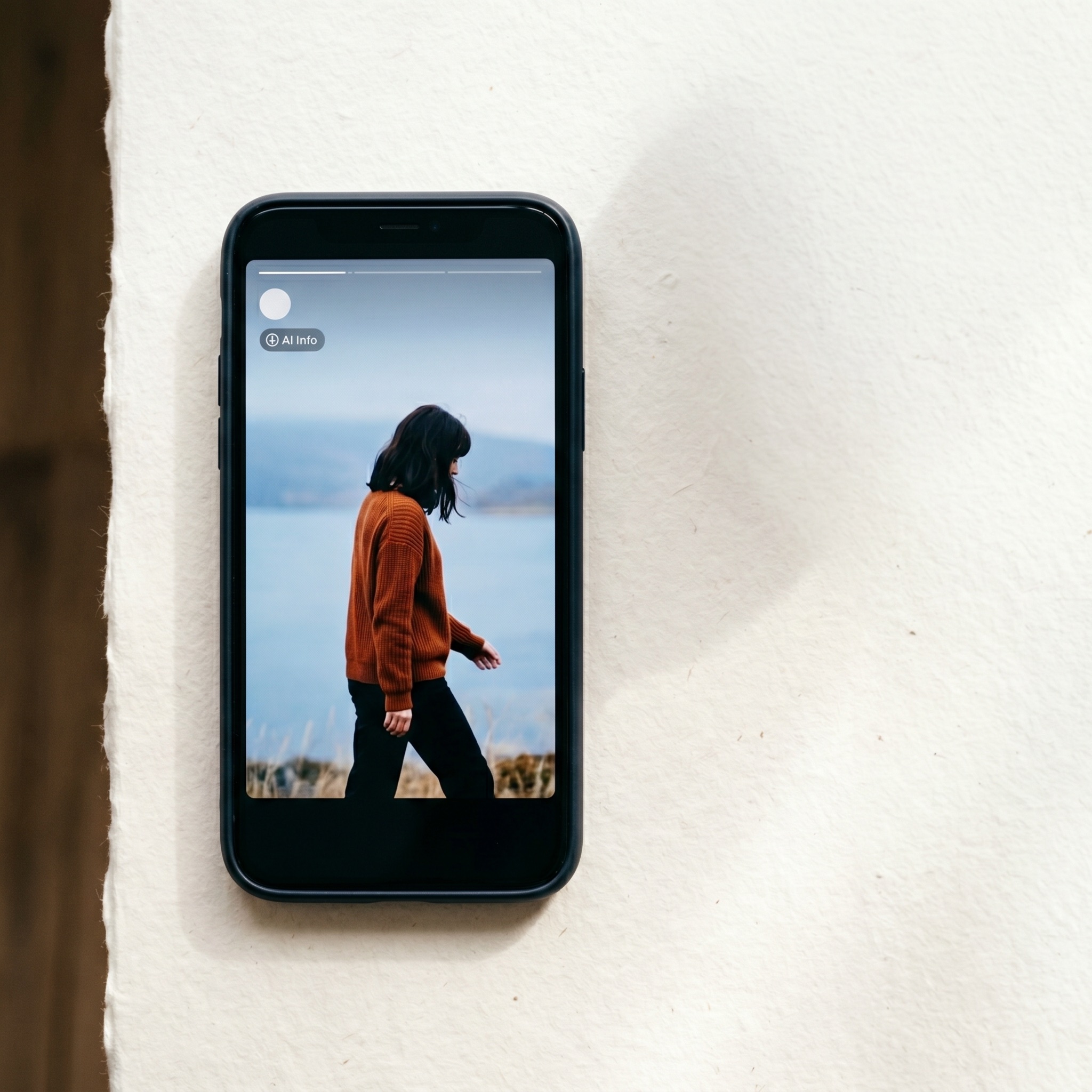 Editorial flat lay of a phone showing a Reels ad with a subtle AI information label visible in the transparency panel.