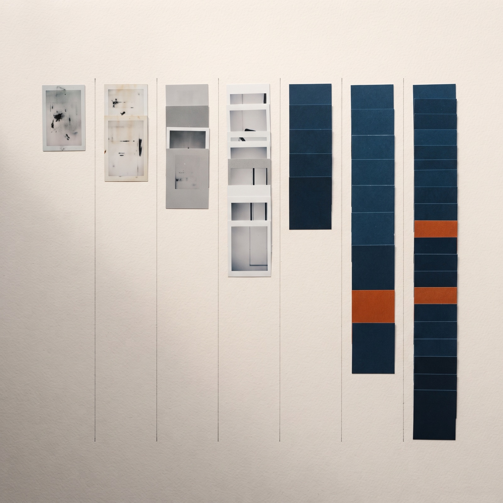 Oversigtsbillede af små printede annoncerammekort arrangeret i syv forskudte kolonner på tværs af en varm hvid overflade, hver kolonne med få kort, og to kort tonet i brændt orange.