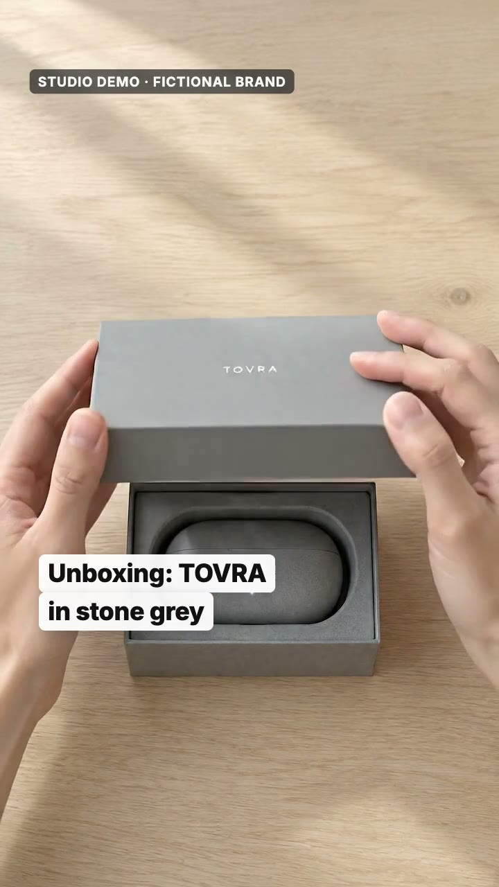 AI-generated studio demo TikTok opening for the fictional audio brand TOVRA: two hands lift the lid of a grey TOVRA box to reveal the stone-grey earbud case, then a first-person view of the open case on a train